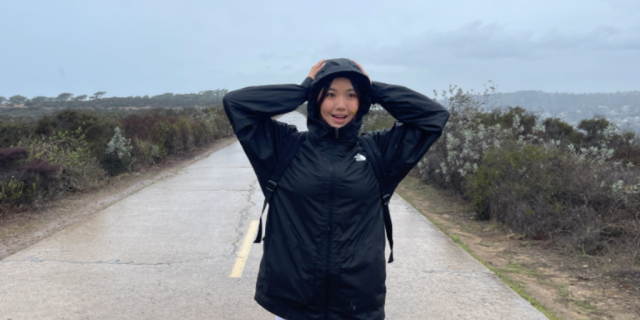 Desang Tenzin wearing a raincoat standing outside on a road on an overcast day.