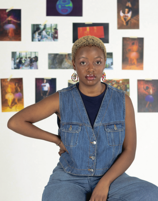 Nosipho Vilakazi sits in a demin outfit in front of a wall covered in photos.
