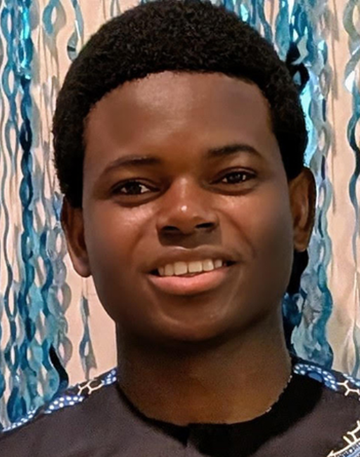 Abdou-Latifou Dare smiles in front of blue party streamers hanging on a wall.