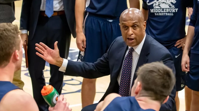 Coach Jeff Brown on the sidelines of a Basketball game talking to players.