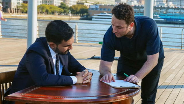 Julian Gerson ’18 and Zohran Mamdani at a desk looking over a speech outside.