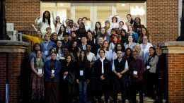 Large group of convening participants stand on steps for a photo