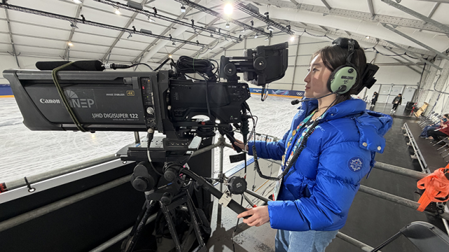 Ting Cui with headset operating a camera in the practice rink at the 2026 Milano Cortina Olympics