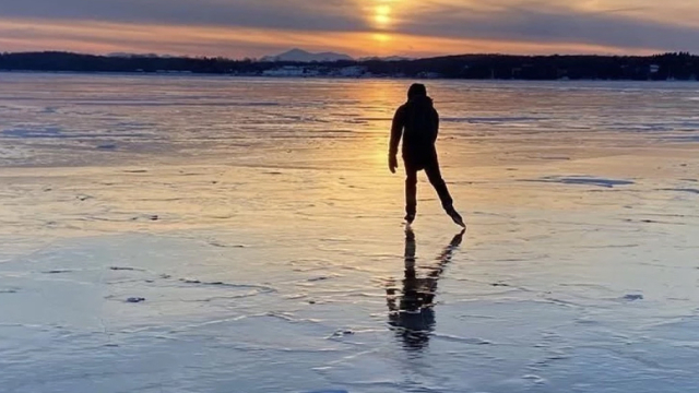 Person skating on a lake at sunset