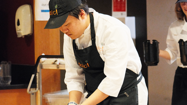 Kurt Le in Dolci apron and chef's coat bending over to plate items