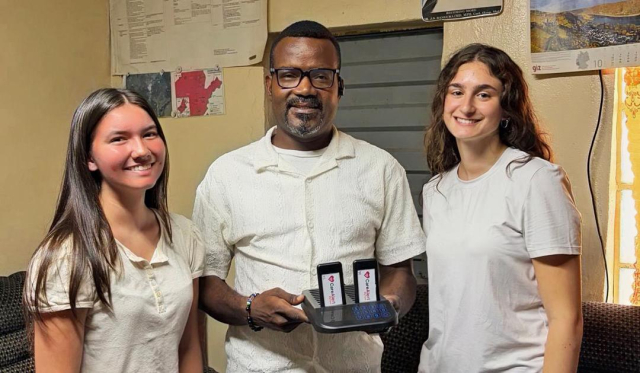 Three people stand facing the camera and smiling