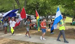People walking in a line on sidewalk holding various national flags.
