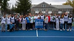 Group of students and athletes on a tennis court pose for a photograph and hold a banner that reads "ACEing Autism"