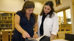 Two women look at archival documents in library