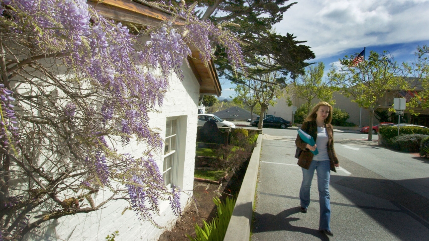 A young woman walks along a path on the Middlebury Institute campus.