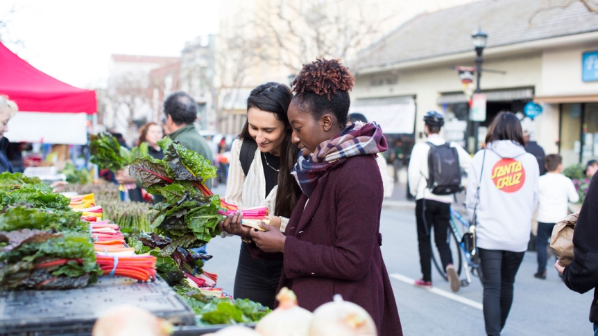 Two students purchase vegetables at the weekly Farmer's Market on Alavarado Street.