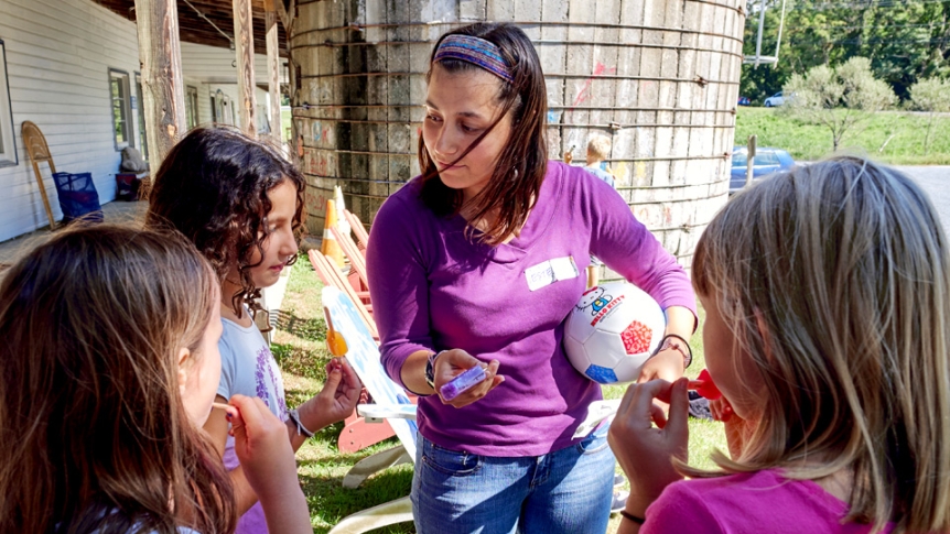 A student works with children outdoors at a local elementary school.