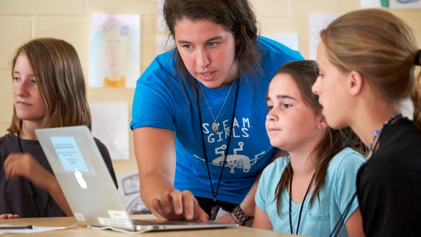 A student coaches elementary school girls as part of a STEAM program.