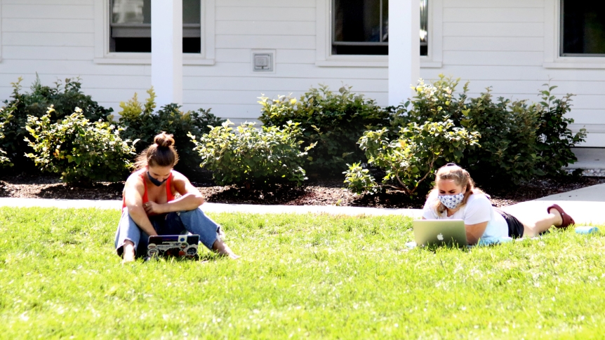 Two Middlebury students sit outside on the lawn.