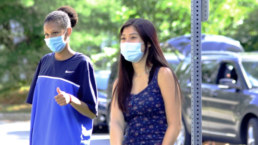 Two Middlebury students walk on campus wearing masks.