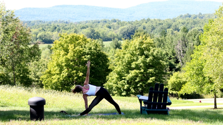 A Middlebury student practices yoga on campus while wearing a mask.
