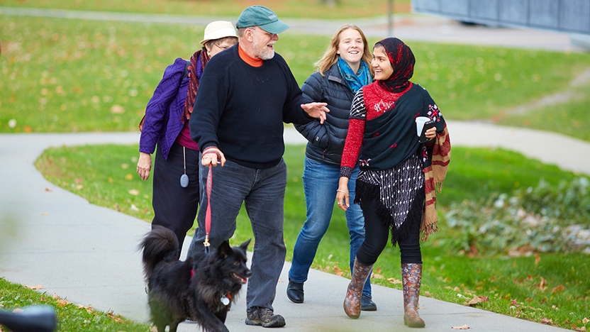 A Middlebury student walks across campus with her parents.