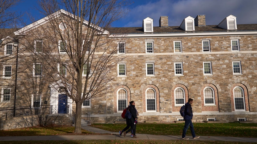 Students walking in front of their dorm on a fall day.