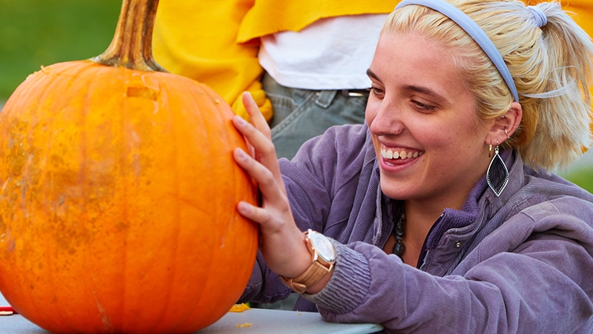 A student carves a pumpkin at Harvest Fest