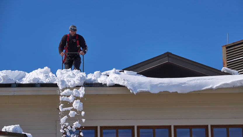 A maintenance worker clears snow from the arts center roof.