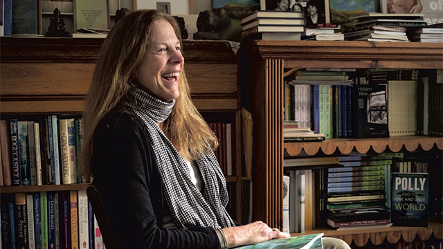 Jean Cummings sitting in profile in front of full bookshelves