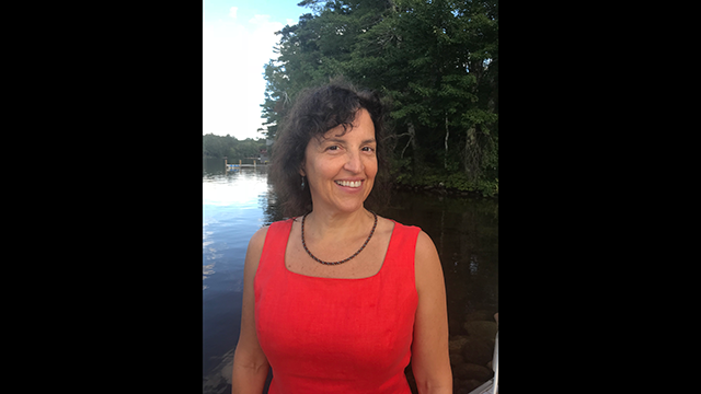 Lisa Davy in sleeveless red top in front of a lake