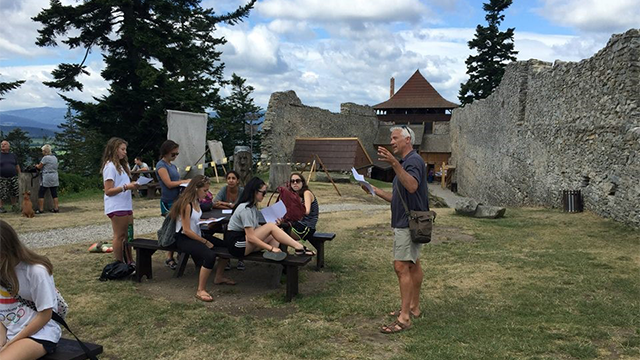 Tim Weed explaining to a tour group outside a stone wall