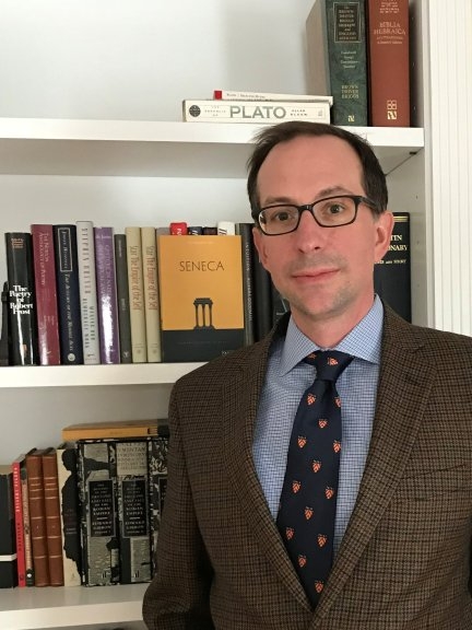 Christopher Star in jacket and tie in front of bookcase