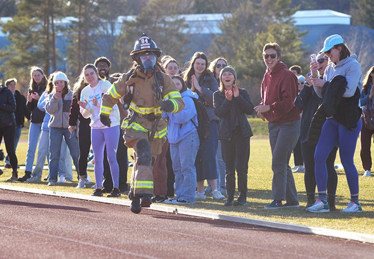 Emily Jones ’23 running in Fire Fighter equipment around the Middlebury track