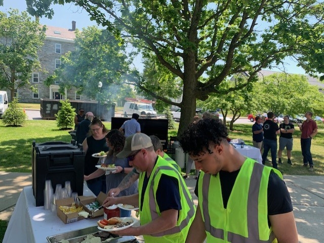 Picture shows staff members in yellow vests getting served food