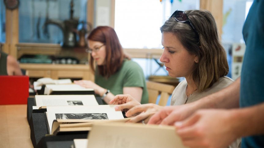 Two women work with special collections texts.  