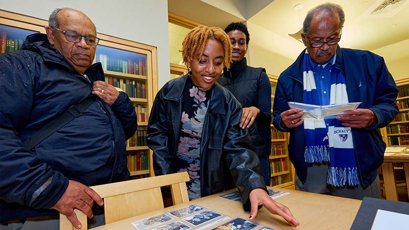 A group of students and alumni look at photos in the Middlebury Archives