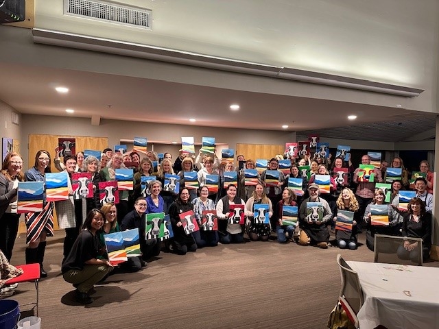 A group shot of all participants with their paintings