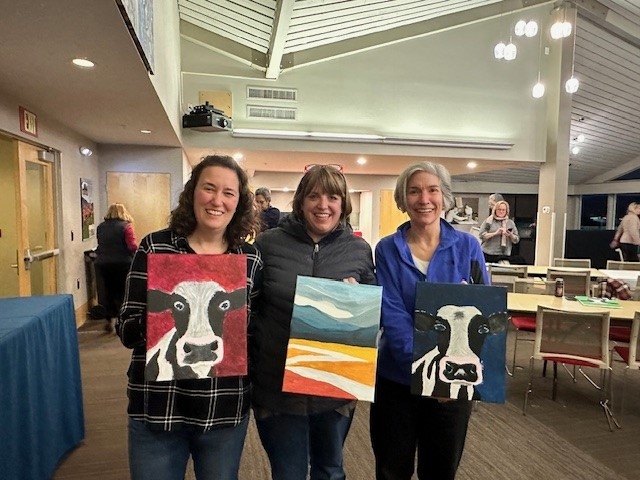 Three participants holding their paintings
