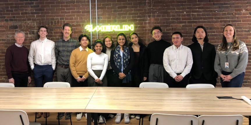 A group of casually dressed students pose behind a conference table as part of theit site visit.