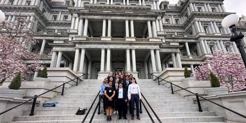 Group of students standing on the White House steps smiling at the camera.