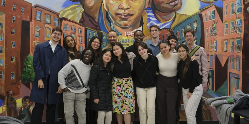 Group of smiling students in front of a mural.