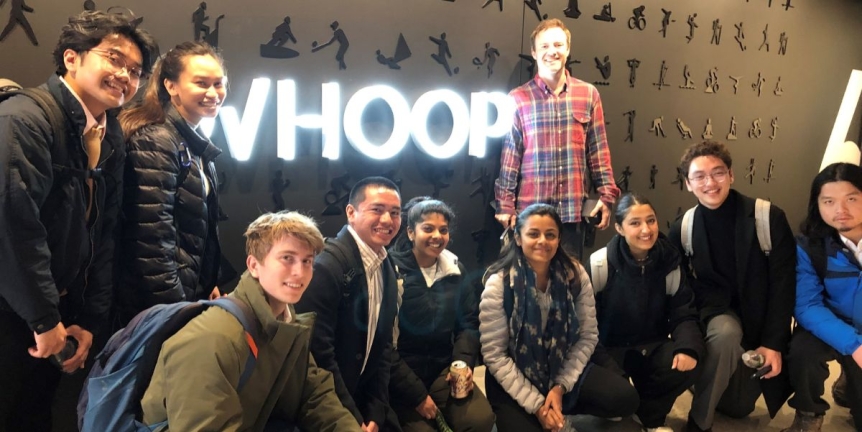Students pose in front of the Whoop neon sign, where the students participated in a weeklong Student Innovation Trek to Boston, MA
