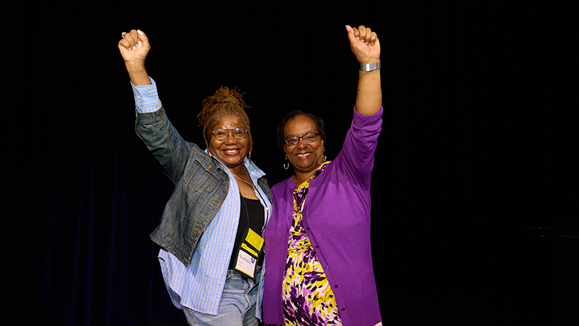 Two classmates and former cheerleaders from the class of 1974 with arms raised in a cheer