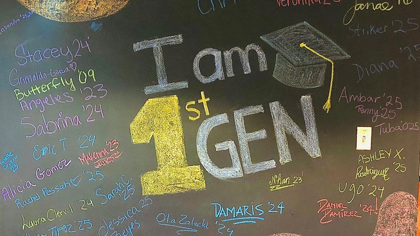 The words "I am First-Gen" written in colored chalk on a black chalkboard.