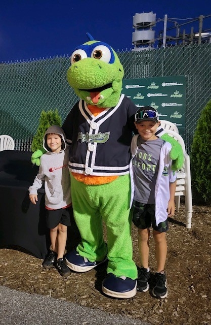 Two young kids standing smiling with Champ