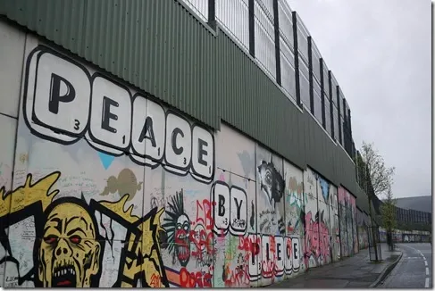 photo of city wall with the word PEACE and images of conflict