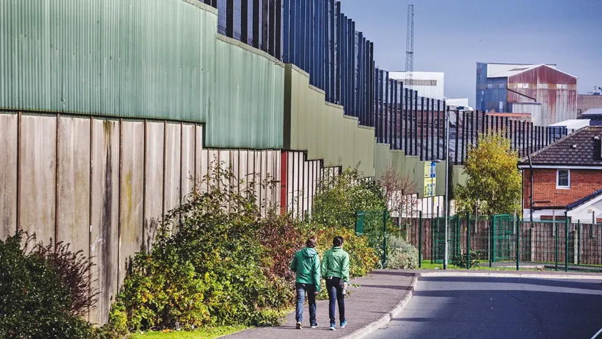 two boys in green shirts walk past barrier walls