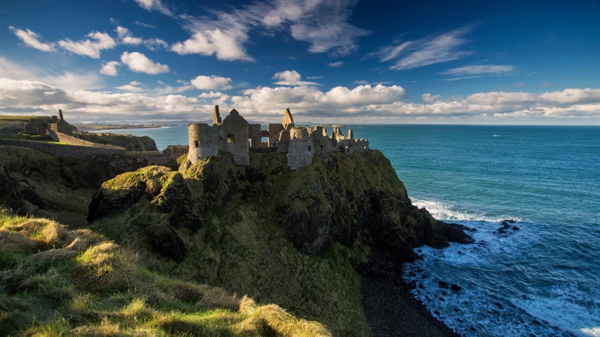 Castle ruin on a headland against blue ocean