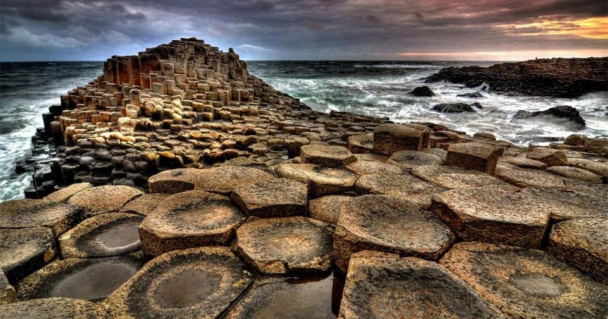hexagonal rock formations with surf and dark skies