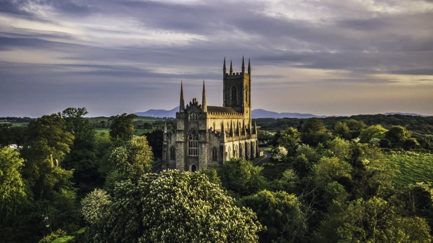 aerial view of gothic cathedral among green trees against a cloudy sky