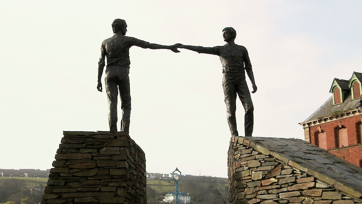 statue of two men reaching toward each other across a divide