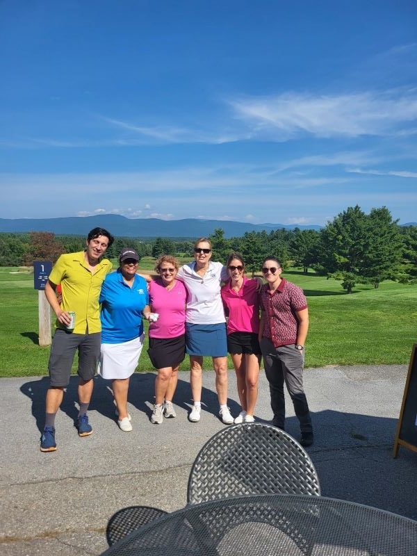 Colleagues standing together playing golf