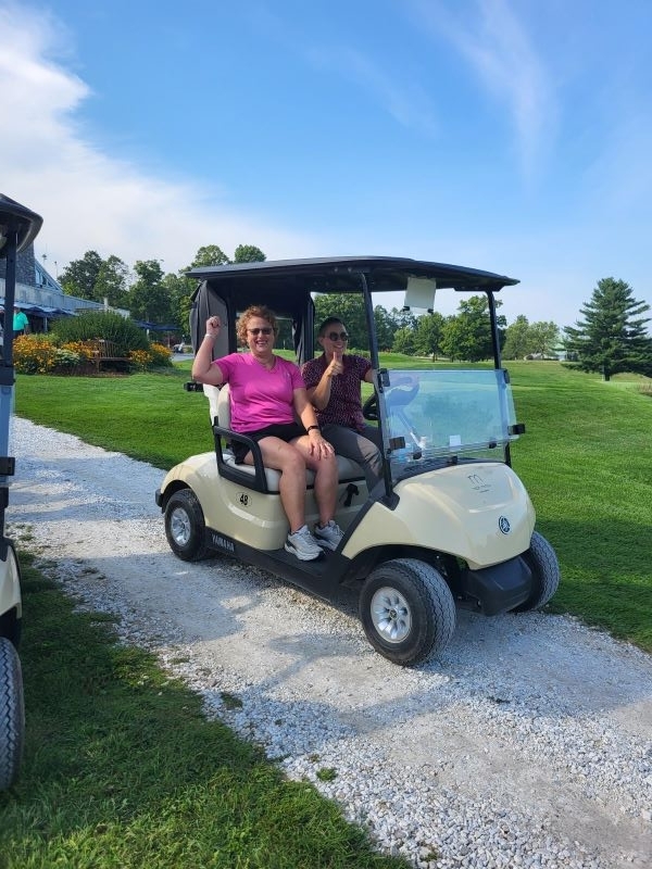 Two colleagues driving golf cart 