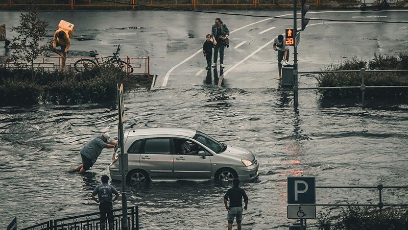 People pushing a van through flooded streets in a city